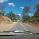 a road with dirt and trees on the side