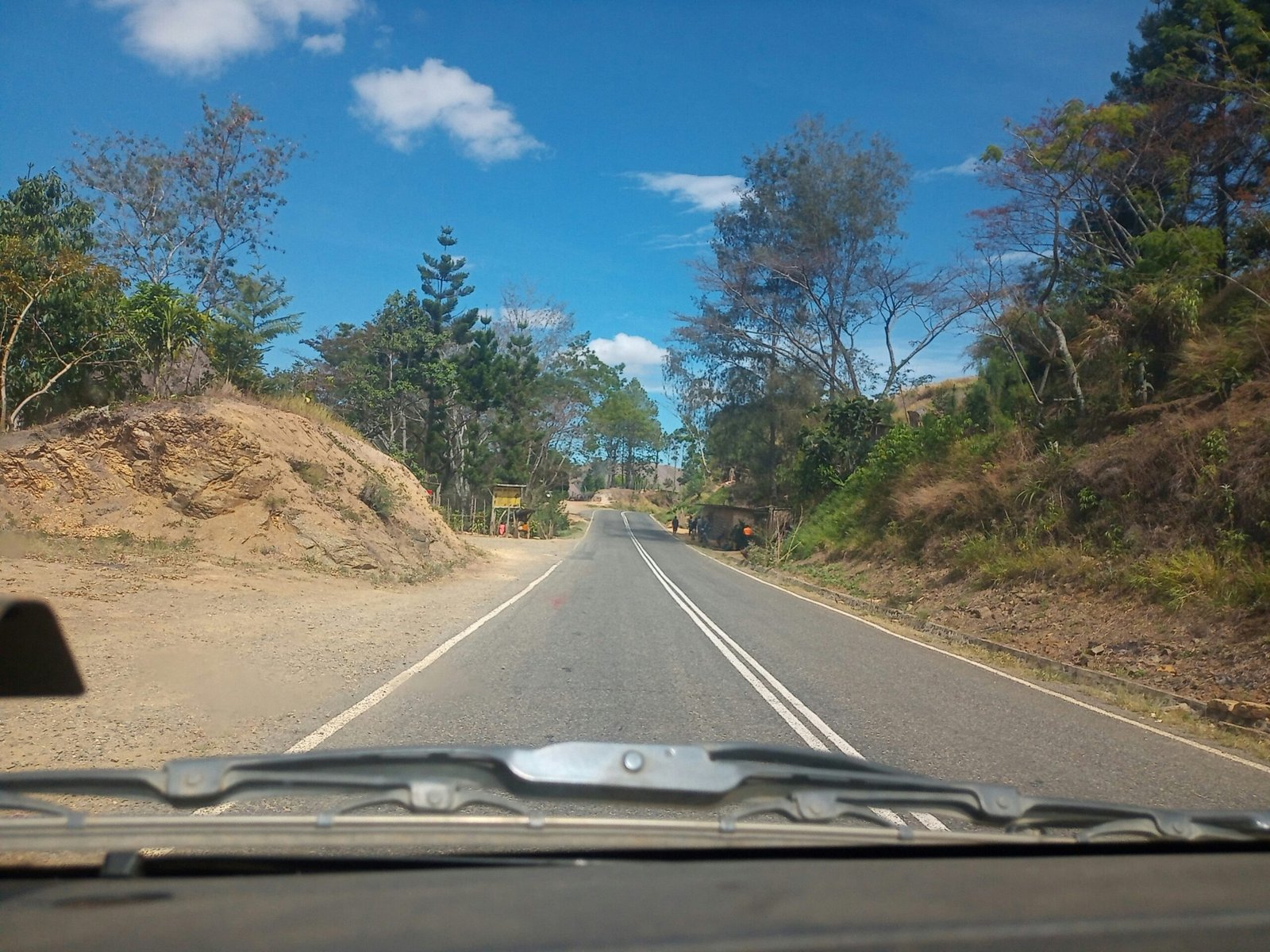 a road with dirt and trees on the side